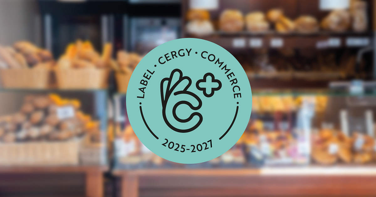 Vitrine d’un commerce affichant le macaron du label Cergy Commerce 2025–2027