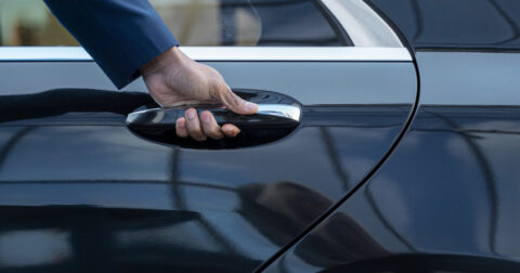 Main ouvrant la portière d'une voiture de taxi